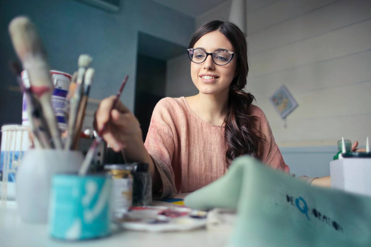 Women dipping a paint brush into a cup of water