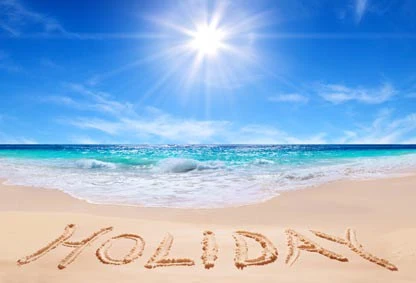 beach with ocean and blue sky with Holday written on the sand.