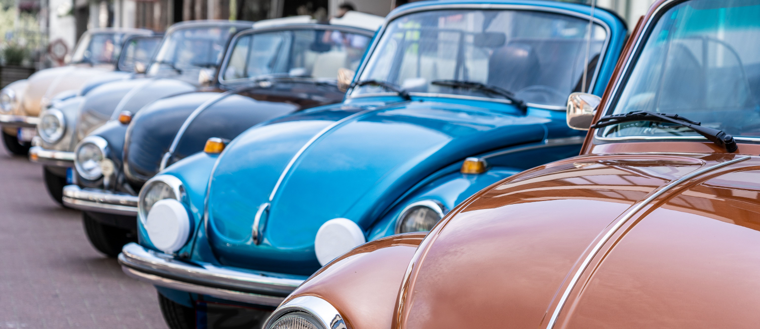 A row of 5 vintage cars parked in a row