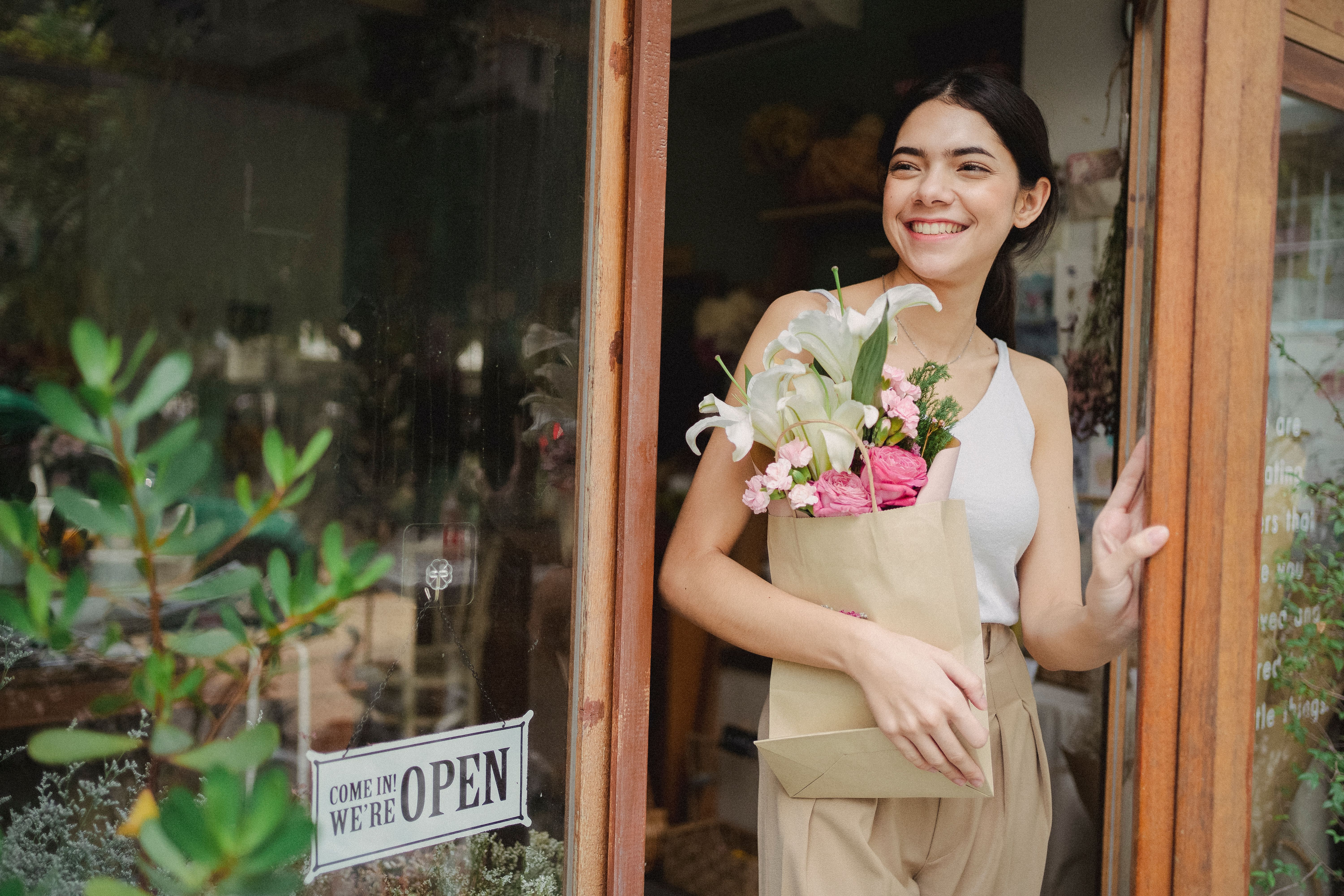 A florist holding a bouquet in front of her flower shop
