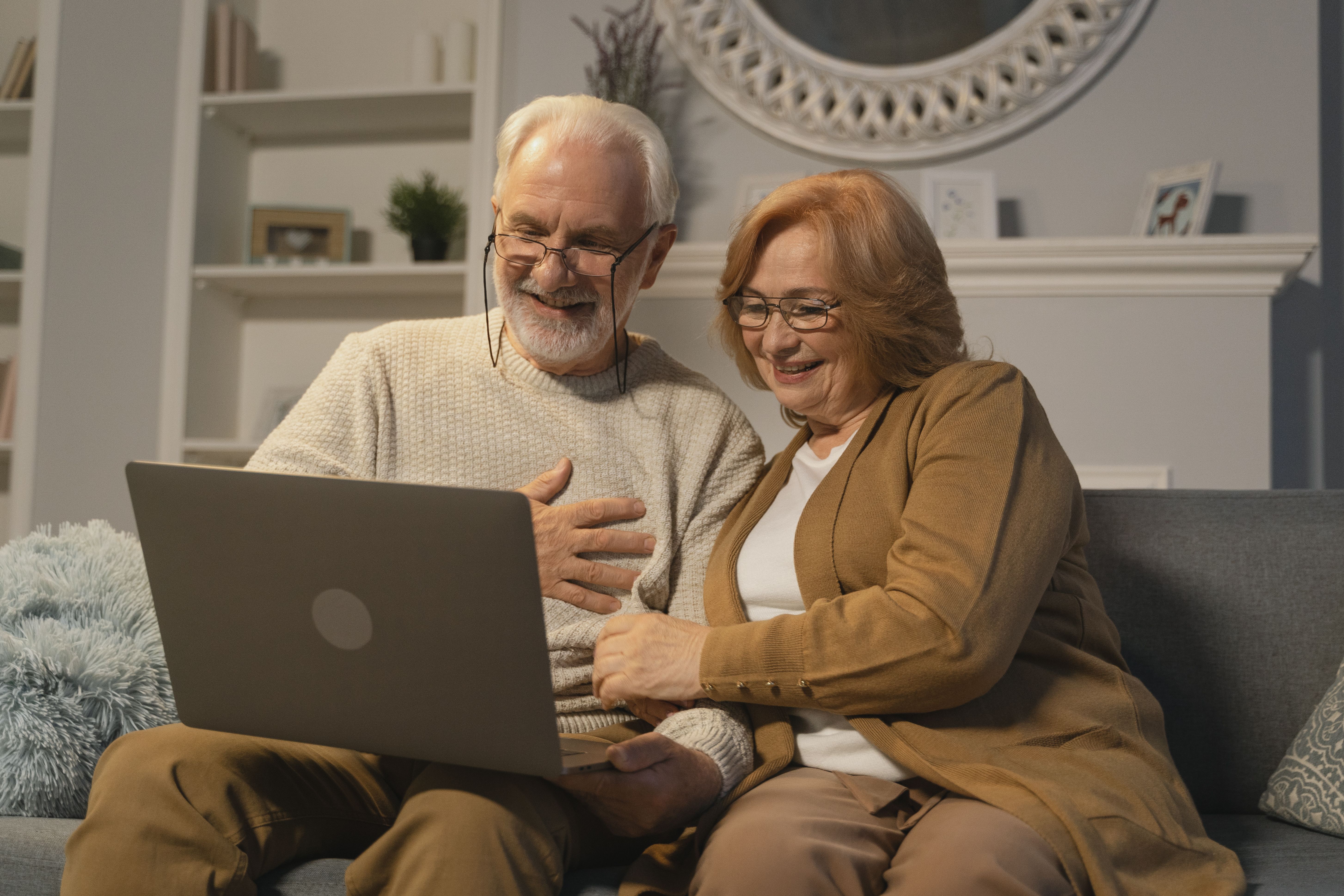 A retired couple looking at a laptop screen and smiling